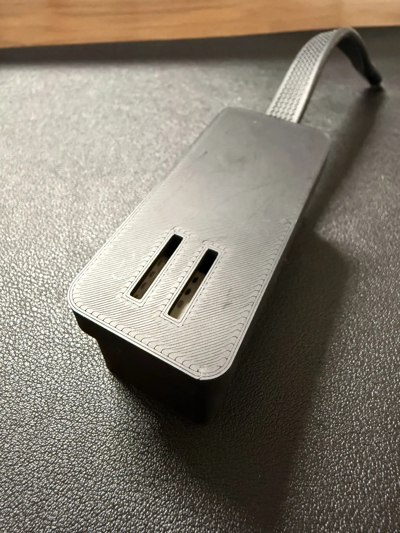 ふたを閉めた黒いケース。上面に縦長の通気口が 2 本あり、奥から USB ケーブルが出ている